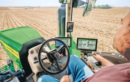 Over-the-operator's-shoulder view of the inside of a tractor traversing a harvested field