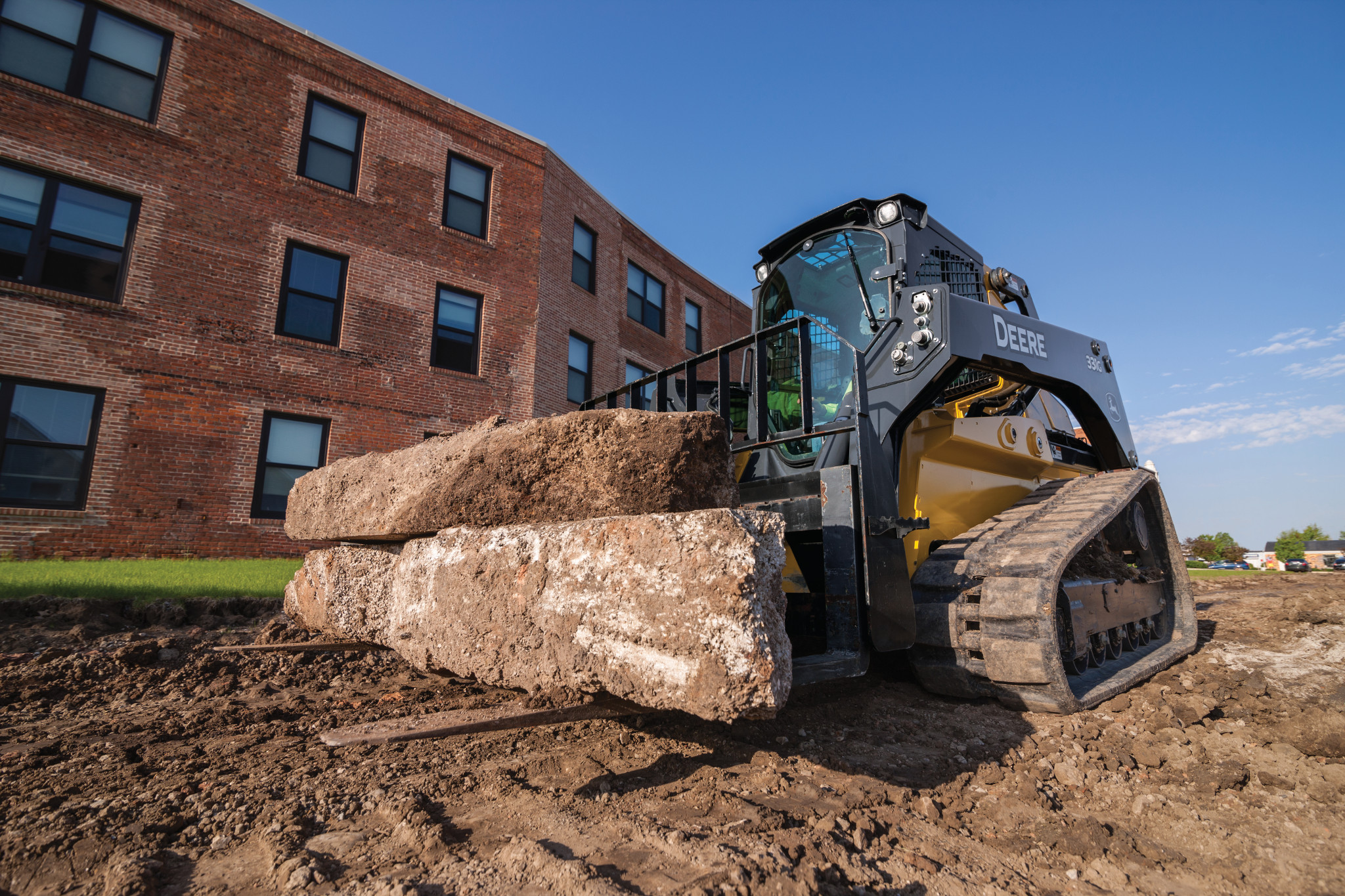 John Deere Skid Steer using pallet forks to move concrete chunks