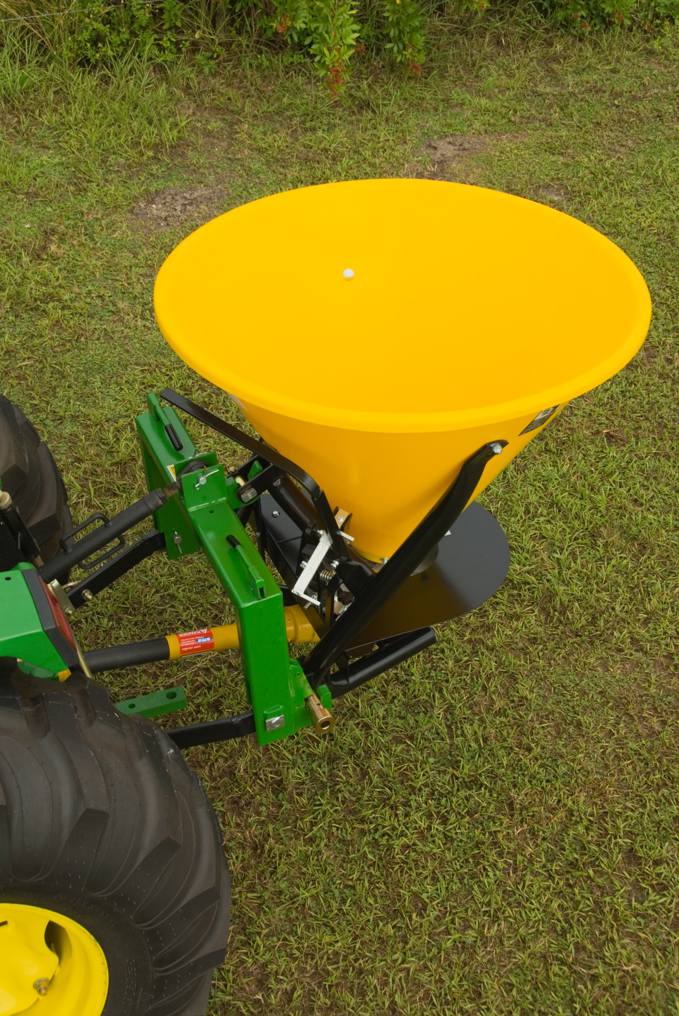 Broadcast spreader attached to the rear hitch of a tractor