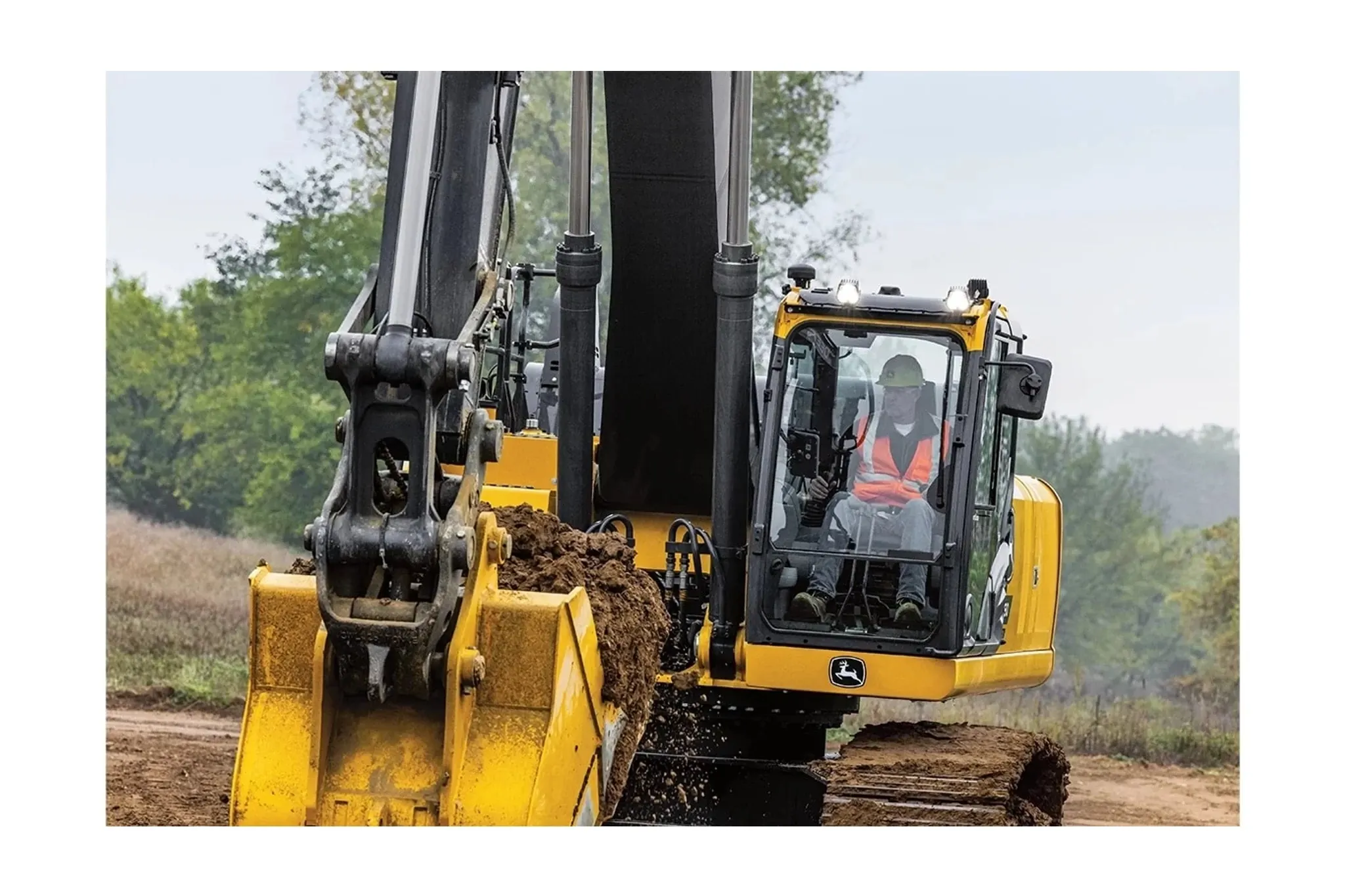 farmer operating a 380 P-Tier Compact Excavator in a dirt field in front of trees