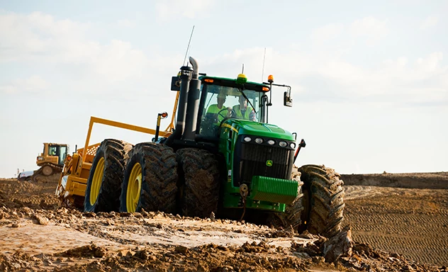 Tractor pulls scraper in field