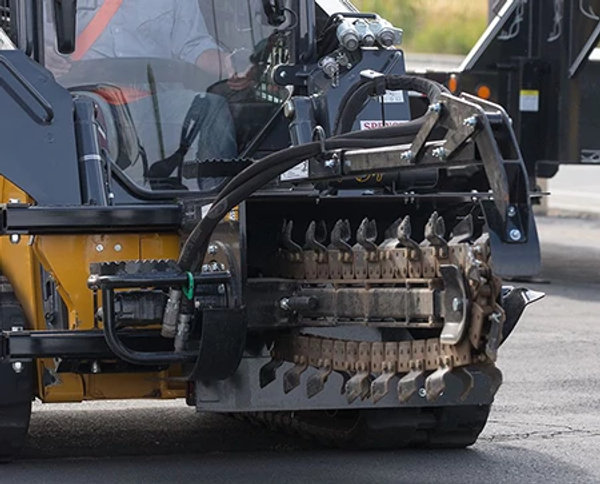 Front view of a TR series trencher attached to a loader traveling down a street