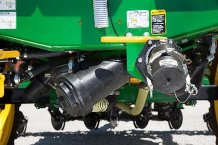 Underside of green liquid applicator showing rinse tank hookup, as well as various hoses and mounting brackets