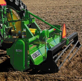 Green Frontier soil‑conditioning or seedbed‑preparation attachment mounted behind a tractor, showing the rear leveling bar and guard with an orange safety slow‑moving vehicle sign visible above the implement.