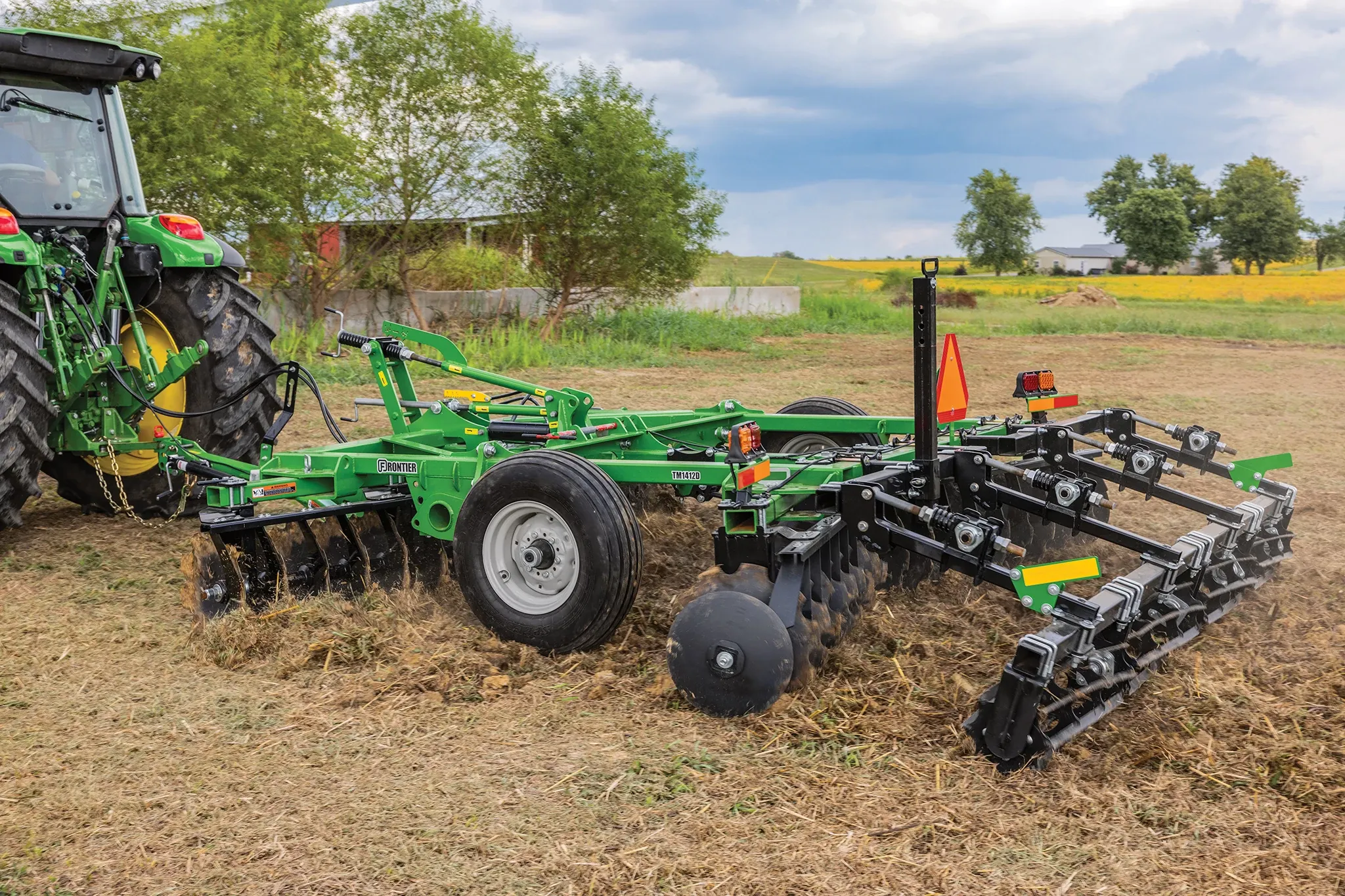 Tractor pulls a TM14 Series Frontier Tandem Disk Harrow in the field.