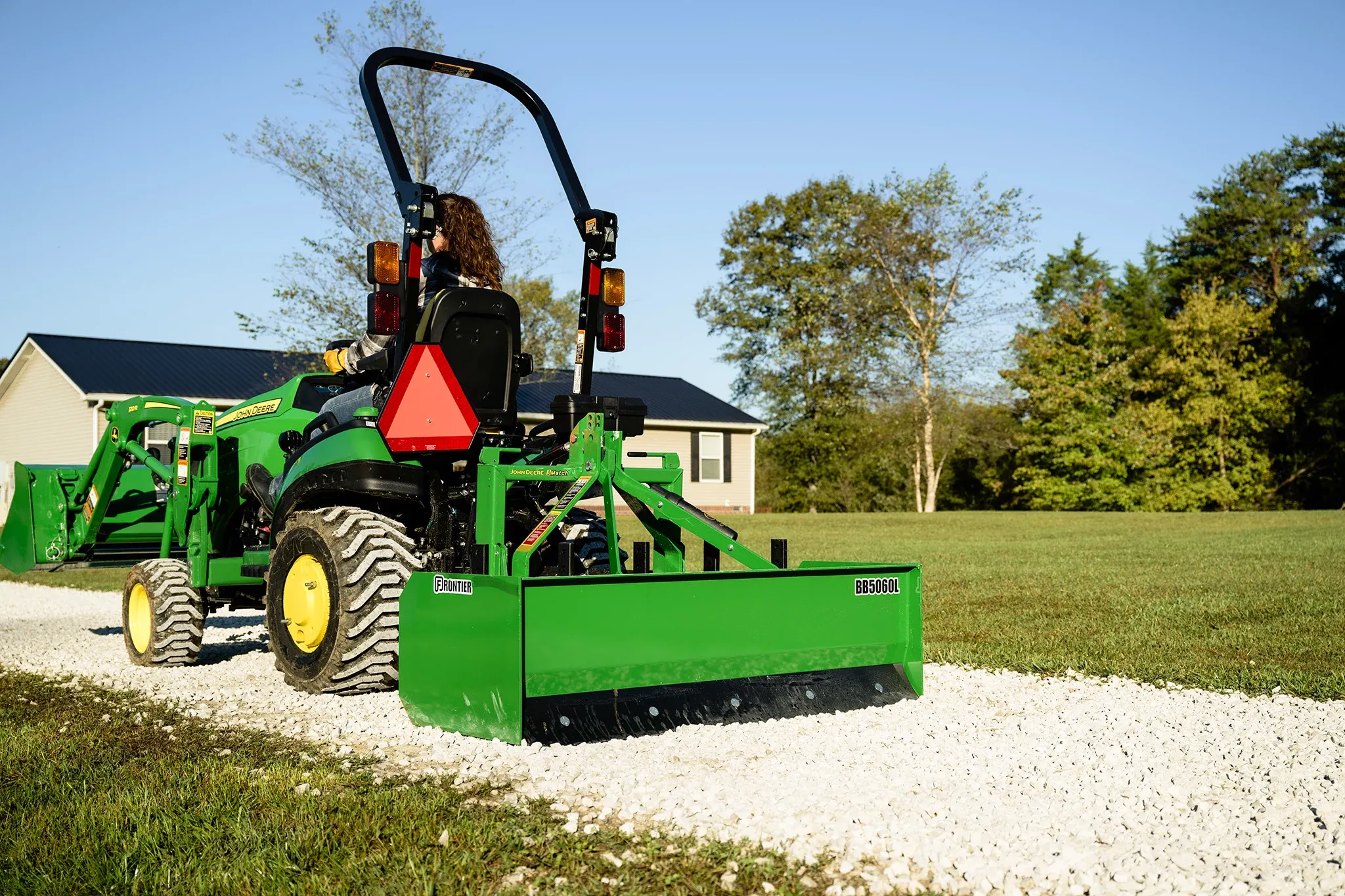 1025R Tractor with BB5060L Box Blade and AY11F Bucket on a gravel walk way