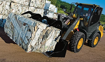 Front left view of a wheel loader using a GS scrap grapple to move cubes of scrap metal