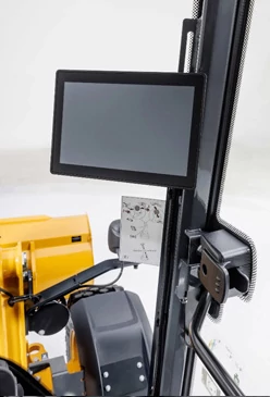 Front left view of a 326 P-Tier Compact Tele-lift Wheel Loader's touchscreen display and corner windows in a studio with yellow bucket in the background