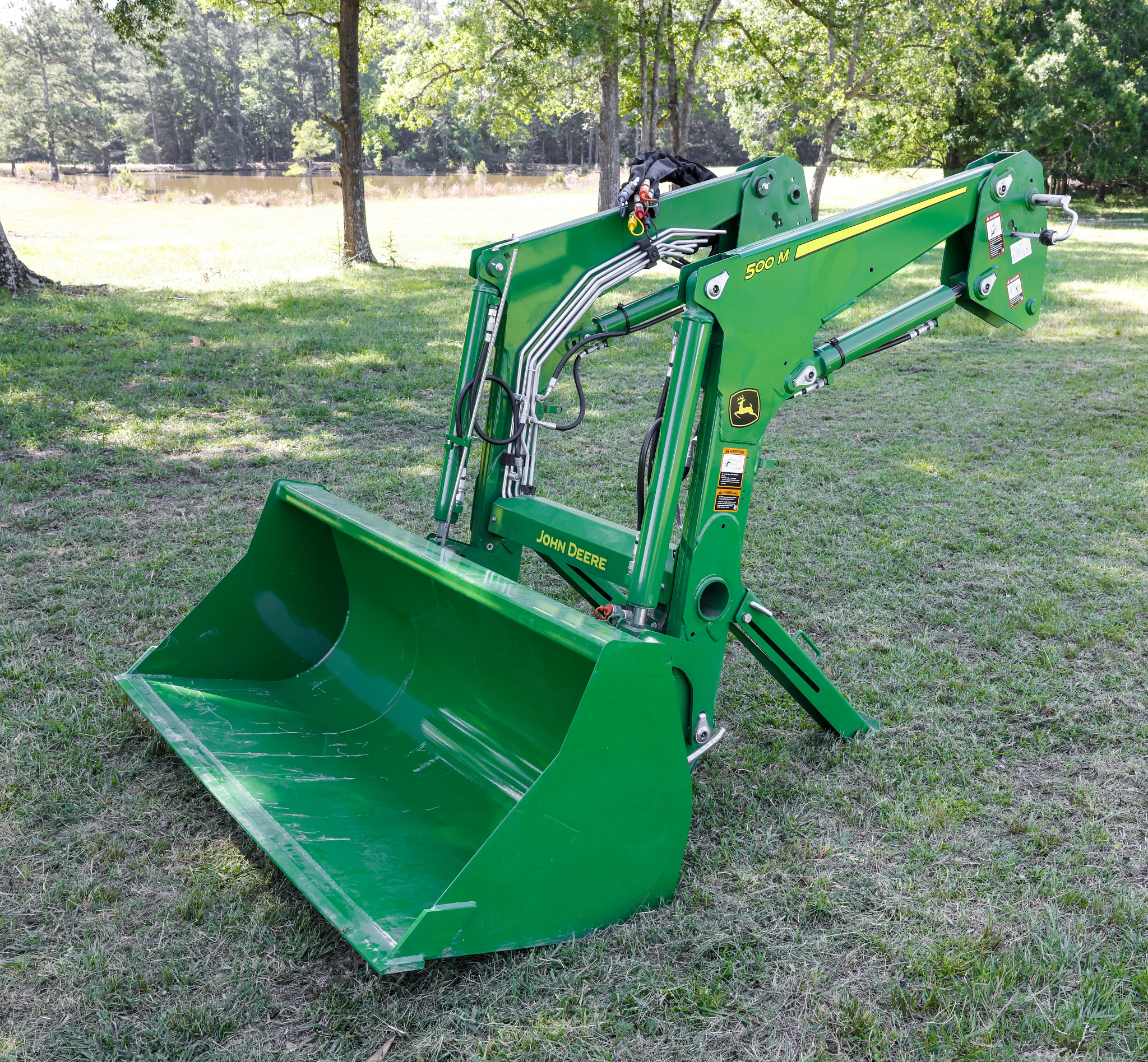 Front left view of a 500M Loader bucket resting on a shaded lawn