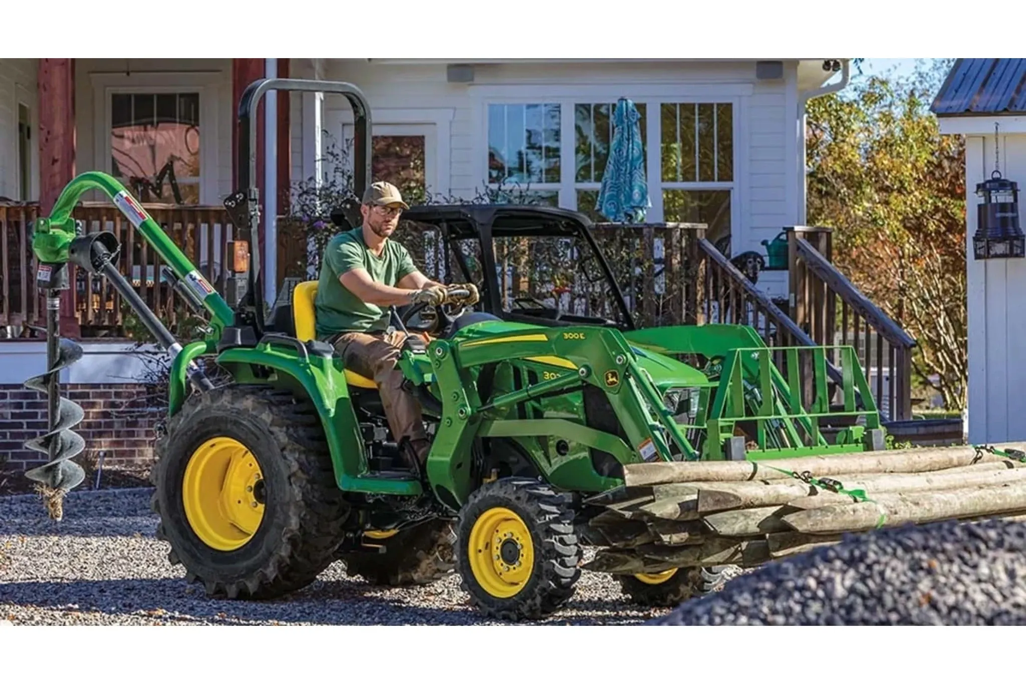 3025E 3 Series Compact Tractors with a farmer driving a tractor with a log loader attached to it