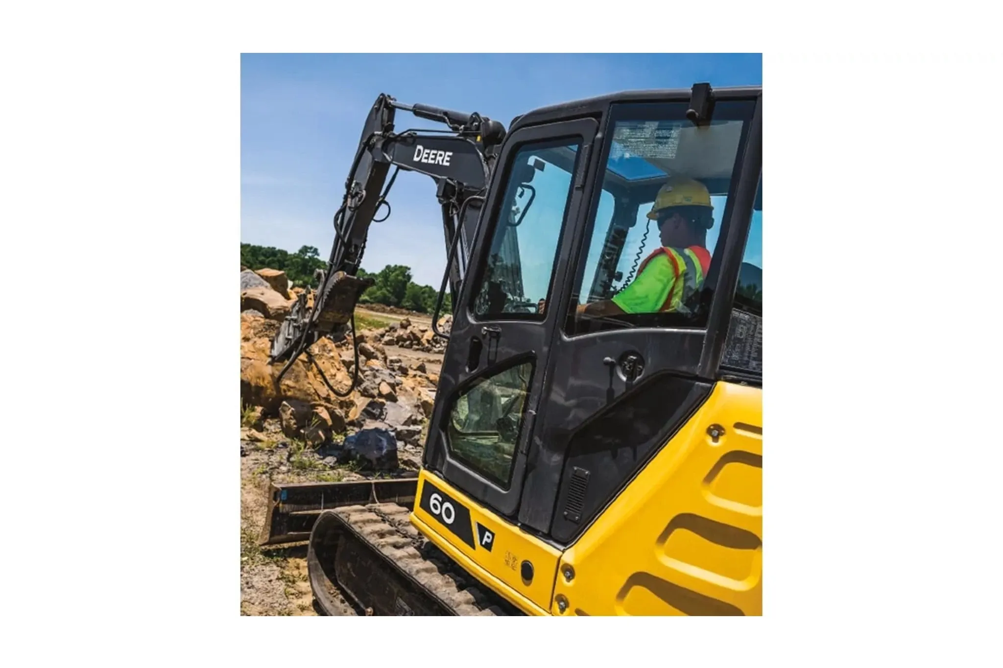 An operator using a 60 P-Tier Excavator to scoop rocks at a worksite