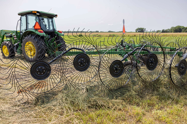 Side left view of a WR3212 wheel rake on hay with attached 5E tractor in the background