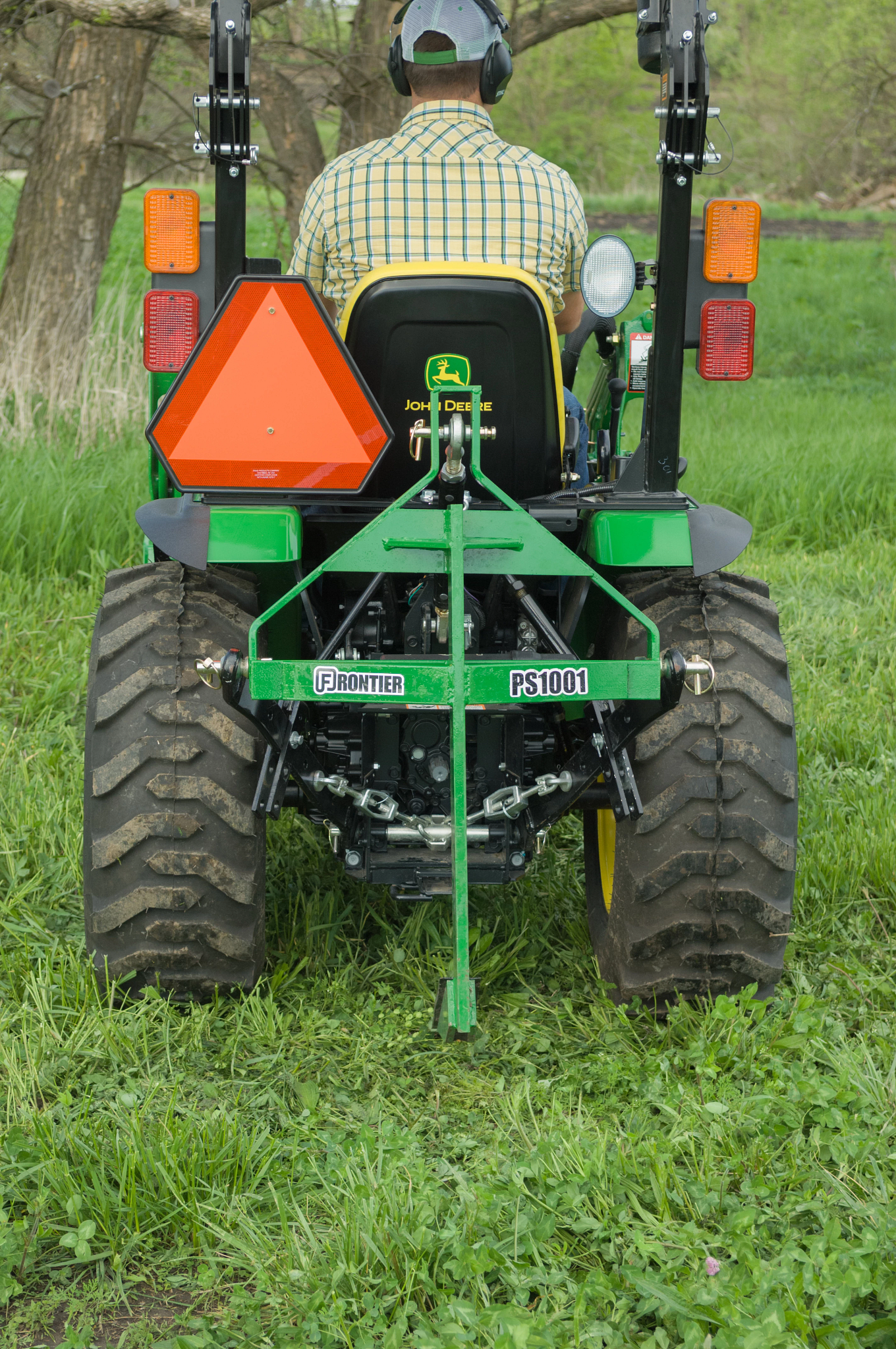 Rear view of a lawn tractor traveling over grass with the PS1001 Integral Subsoiler attached