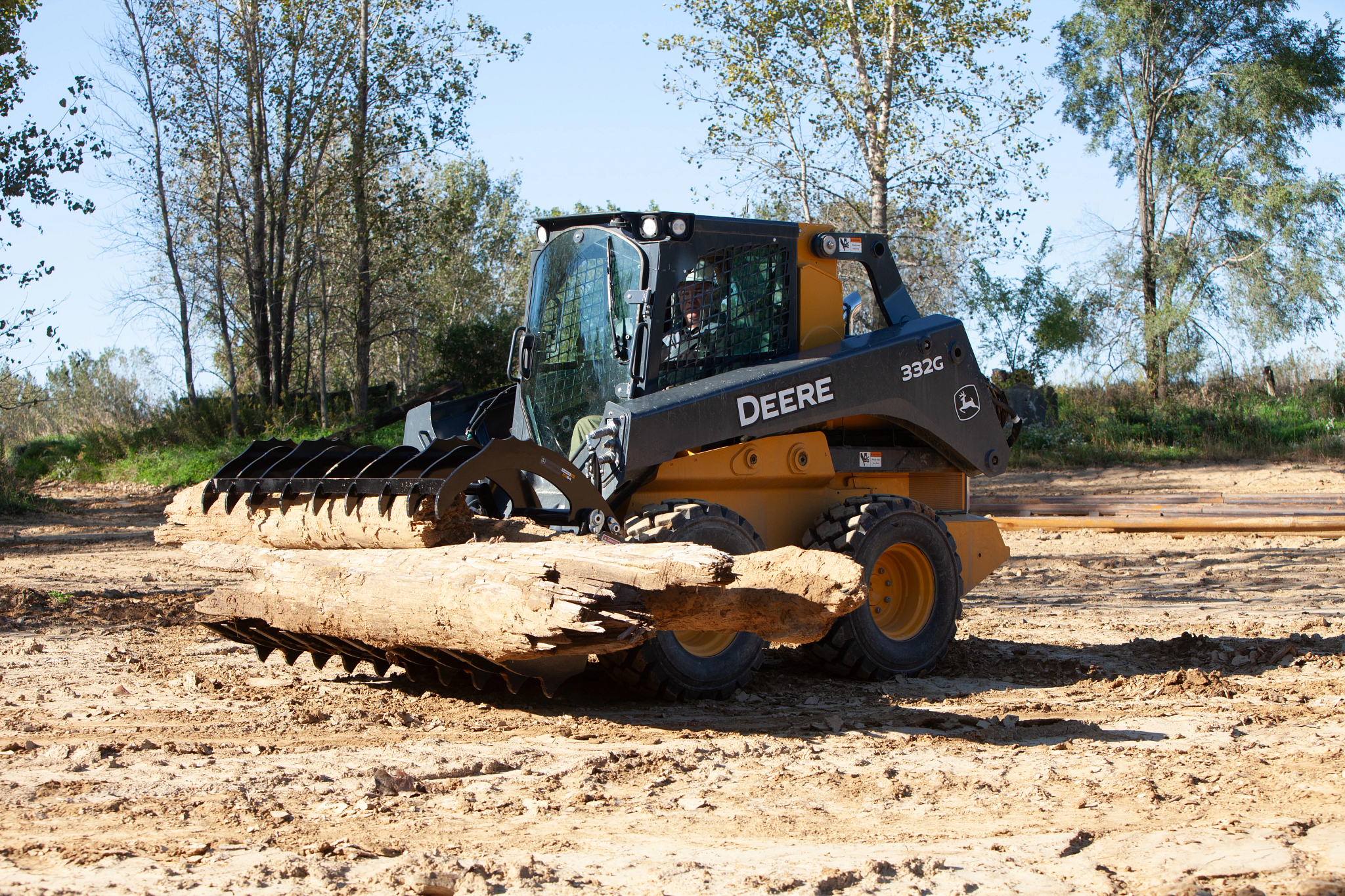 Side left view of an RR84 Root Rake clutching logs on a 332G Skid Steer
