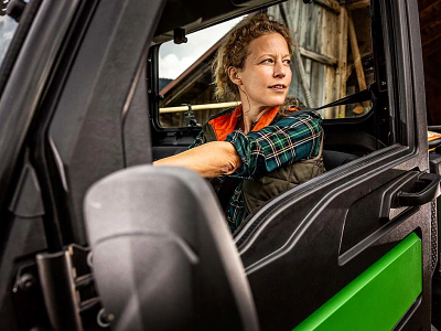 A woman at the wheel of a green and black jeep, embodying freedom and exploration on an open road.