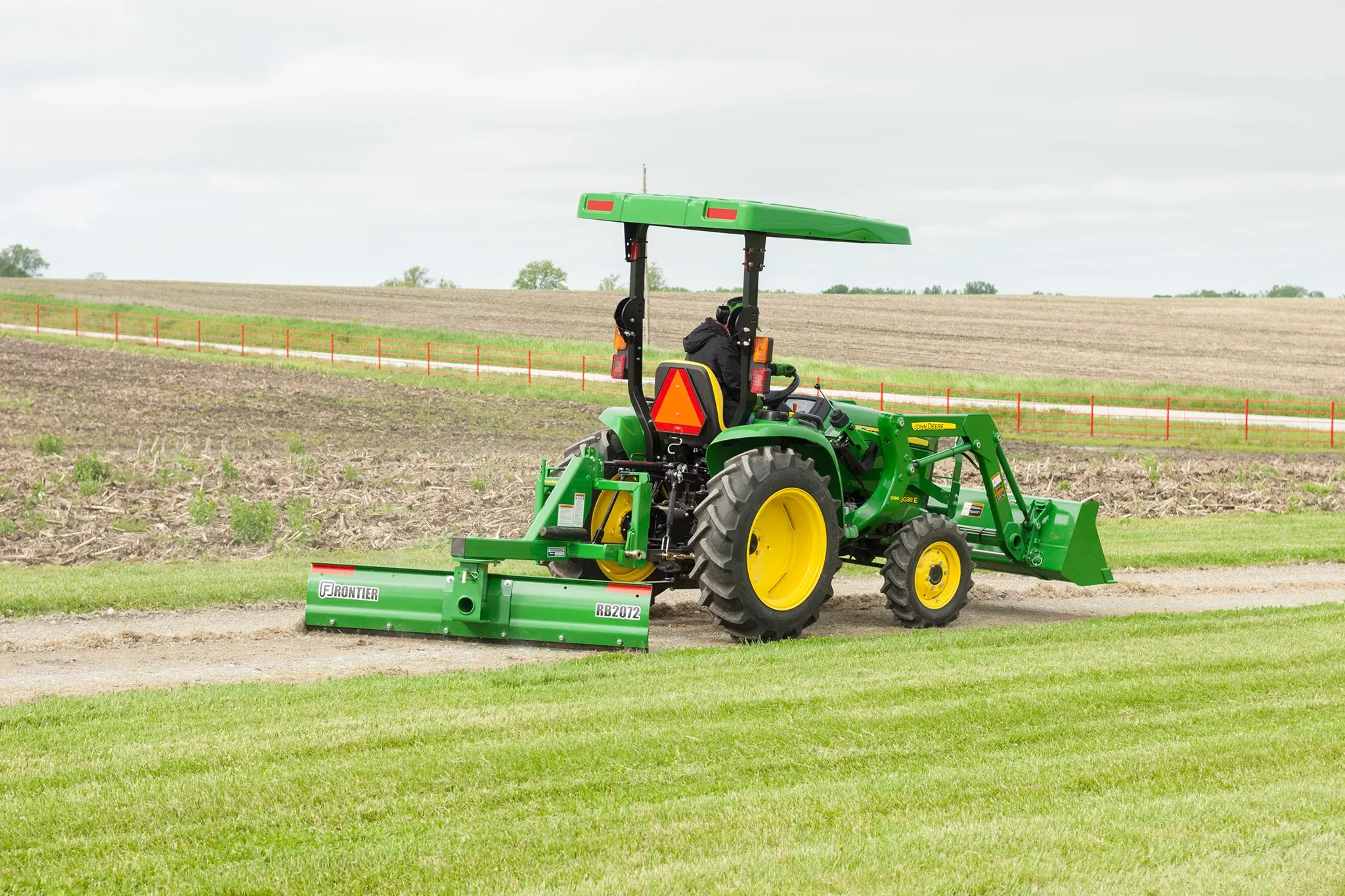 3038E Tractor with rear blade and front loader on dirt drive