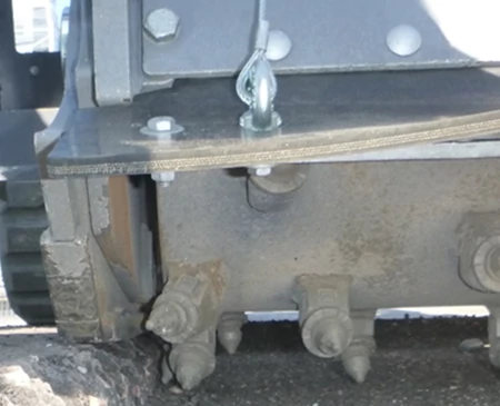 Front close-up of a cold planer against a low curb utilizing 2-in. zero edge measurement
