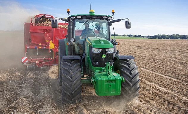 Front view of a tractor pulling a potato harvester through a field
