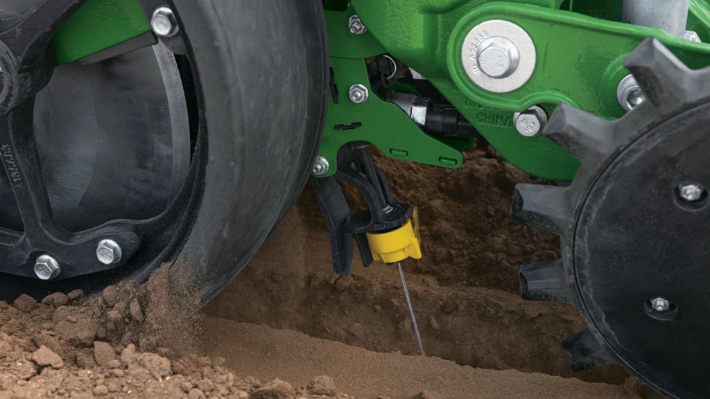 Close-up of a John Deere planter row unit placing seed in the soil — Koenig Equipment