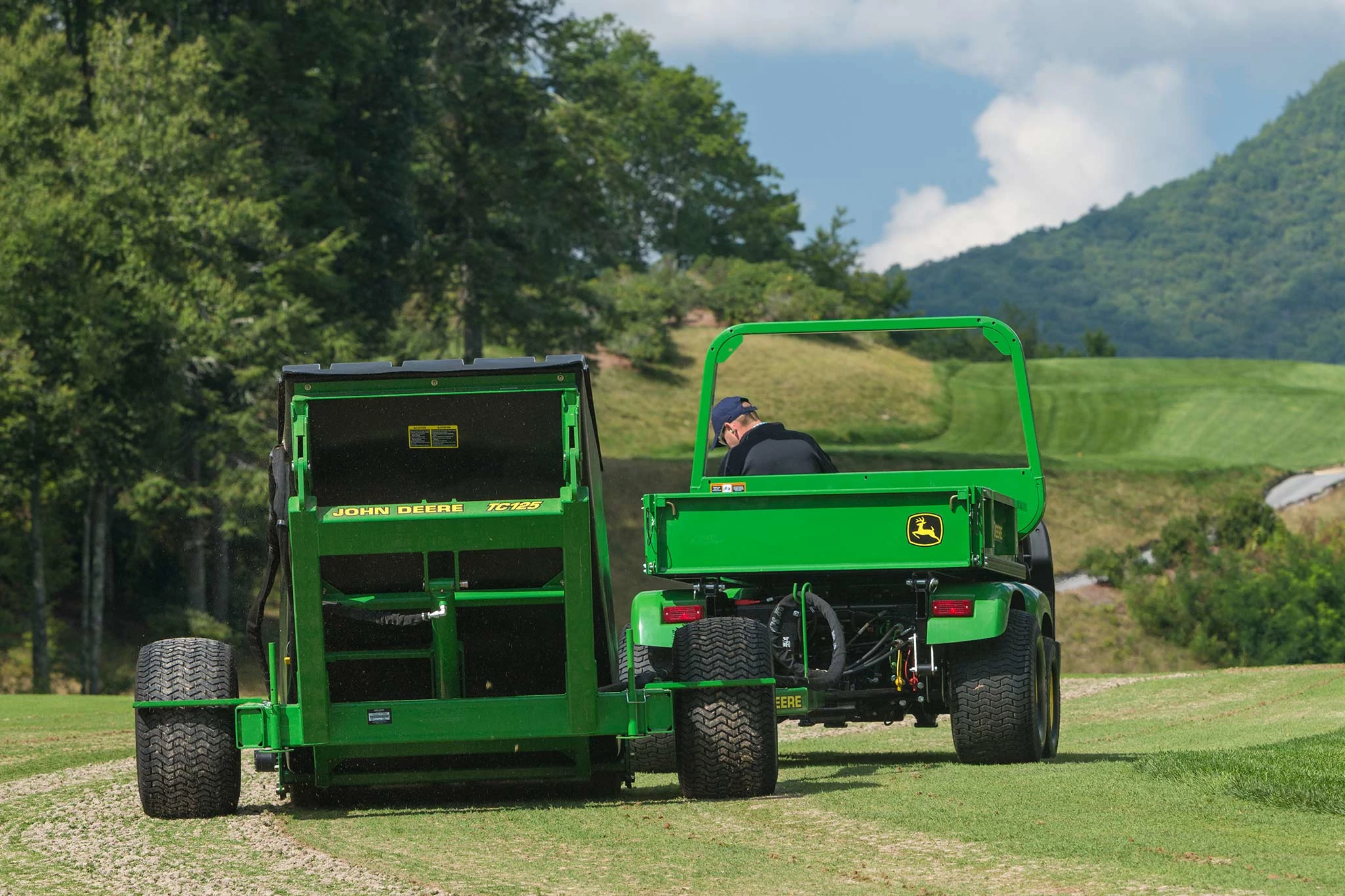 Rear view of a green 2020A ProGator using a left-side attached TC125 turf collection system on a mountain top golf course