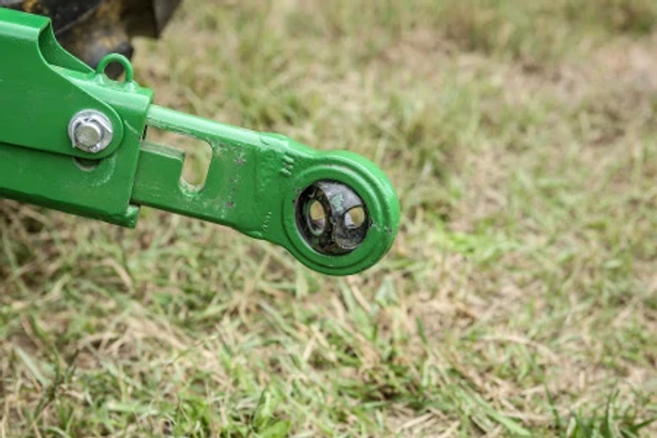 Side, close-up view of a 4M heavy duty tractor's 3-point rear hitch with grass background