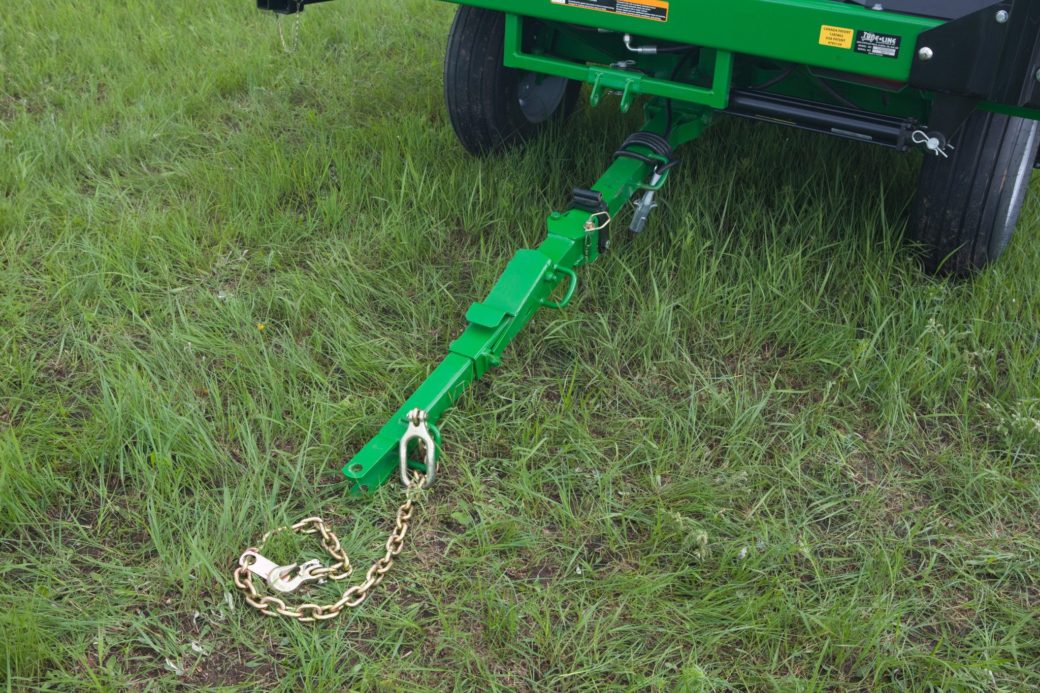 Front left view of an LW1266 inline bale wrapper's hitch and adjustable tongue with grass background
