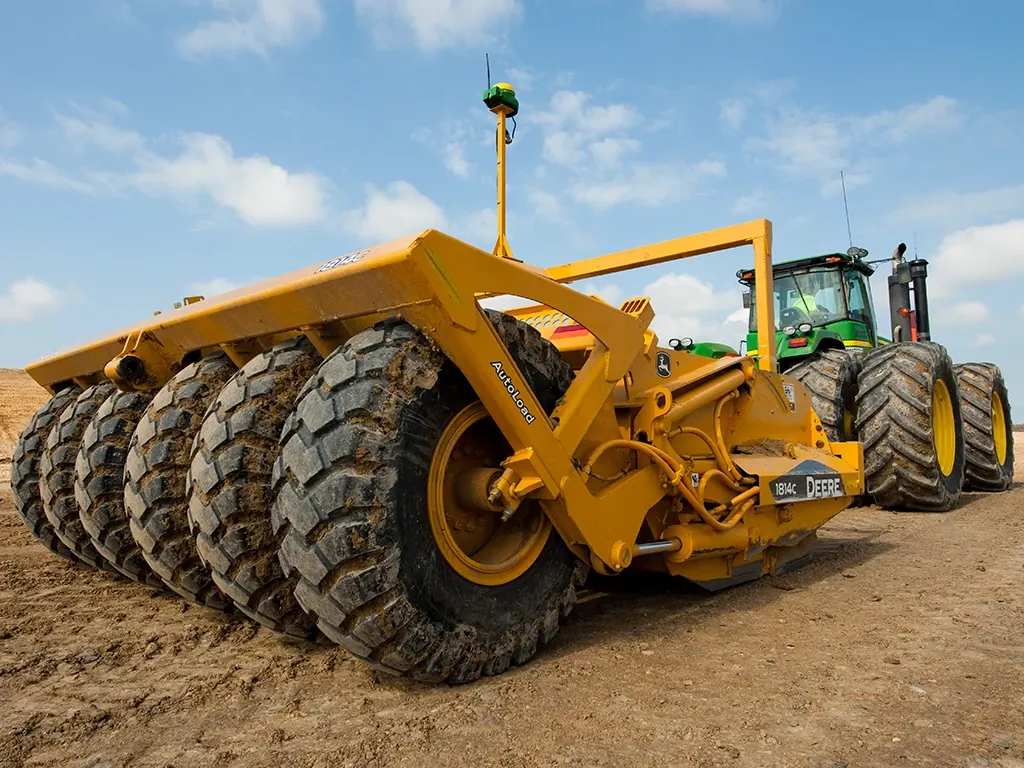 Tractor pulls a scraper in a field
