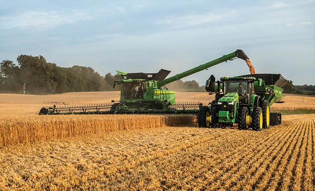 Combine auger filling grain cart in a field
