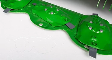 Studio close-up of an F300R's green cutterbar, featuring its quick change knives